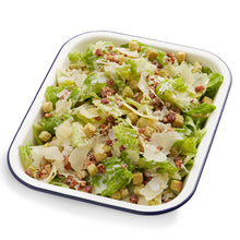 Load image into Gallery viewer, A serving of classic Caesar salad with crisp lettuce, Parmesan shavings, bacon, and croutons, dressed with a creamy Caesar dressing, served in a white dish with a blue rim.