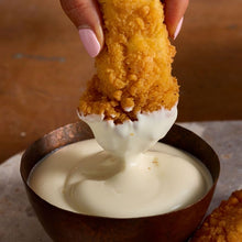 Load image into Gallery viewer, Fried chicken being dipped into a bowl of white sauce.