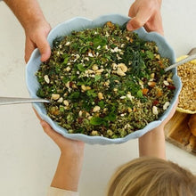 Load image into Gallery viewer, Person holding a bowl of salad with greens and nuts on a light background