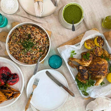 Load image into Gallery viewer, Dinner table with roasted chicken, Persian rice salad, and grilled vegetables on a beige tablecloth.