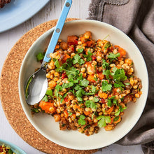 Load image into Gallery viewer, Spiced Israeli Couscous topped with fresh coriander in a round white bowl and spoon