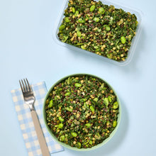 Load image into Gallery viewer, A green bowl and plastic container filled with Green Goddess salad on a light blue background.