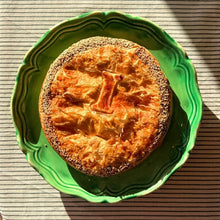 Load image into Gallery viewer, Round baked dish on a green plate with a striped background