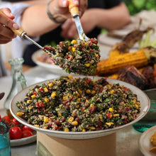Load image into Gallery viewer, Mexican Quinoa Bean Salad with hands serving a portion in salad servers