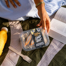 Load image into Gallery viewer, Person holding a lunch container with food on a picnic blanket