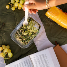 Load image into Gallery viewer, Person eating a salad from a container with grapes and a book on a green surface