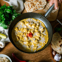 Load image into Gallery viewer, Satay Chicken in a pan on a wooden table with tortillas and herbs.
