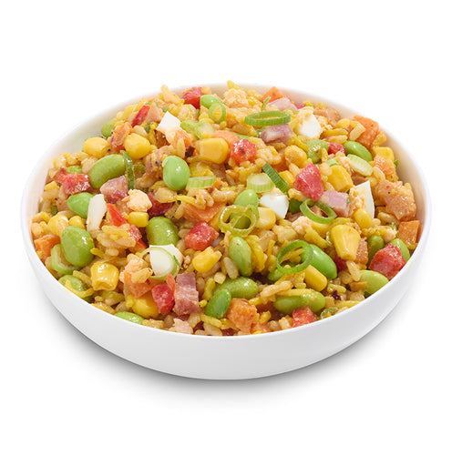 Colorful salad with bacon, corn, green beans, and other vegetables in a white bowl on a white background