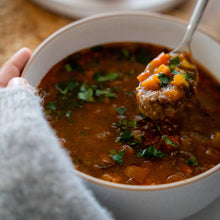 Load image into Gallery viewer, Bowl of hearty lentil soup with carrots and herbs. 
