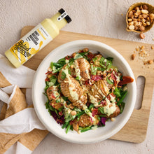 Load image into Gallery viewer, A bowl of salad with grilled chicken and creamy dressing sits on a wooden cutting board, with a bottle of Salad dressing and a small bowl of peanuts nearby on a light textured surface.
