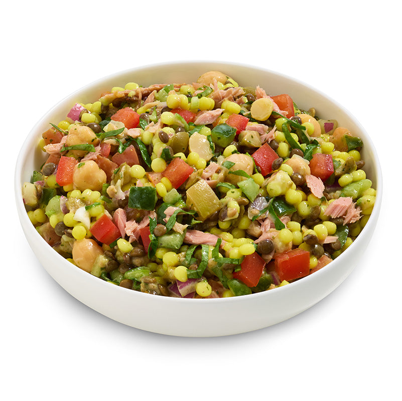 Colourful salad with vegetables and tuna in a white bowl on a white background