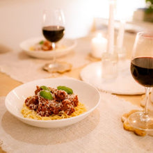 Load image into Gallery viewer, Dinner table with spaghetti dish and red wine glasses

