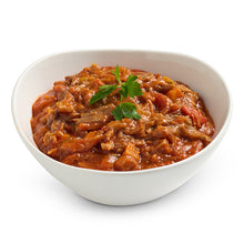 Load image into Gallery viewer, A white bowl filled with a chunky red-orange stew or curry containing visible meat and vegetables, topped with a small green herb garnish, on a clean white background.
