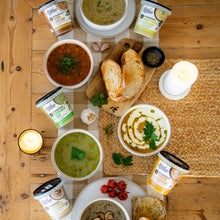 Load image into Gallery viewer, Assorted bowls of soup with bread and candles on a wooden table
