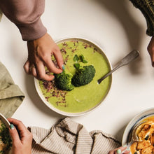 Load image into Gallery viewer, Green Soup with broccoli onto with hand reaching for it
