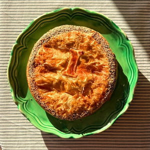 Round baked dish on a green plate with a striped background